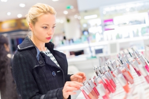 Beautiful blond lady testing and buying cosmetics in a beauty store.