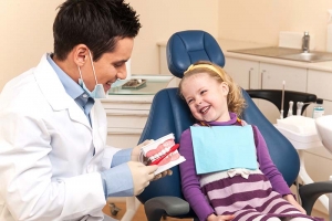 Маленькая девочка осматривает зубы стоматологом