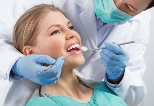 치은염 치료. 여성의 어금니를 검사하는 남성 외과 의사